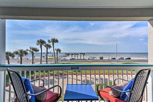 balcony with a water view and a view of the beach