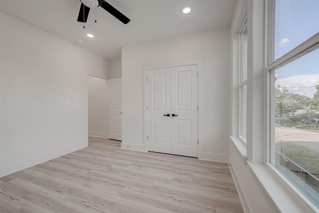 unfurnished bedroom with ceiling fan, light wood-type flooring, and a closet