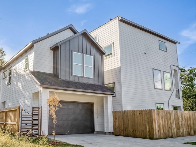 exterior space with a garage, fence, board and batten siding, and driveway