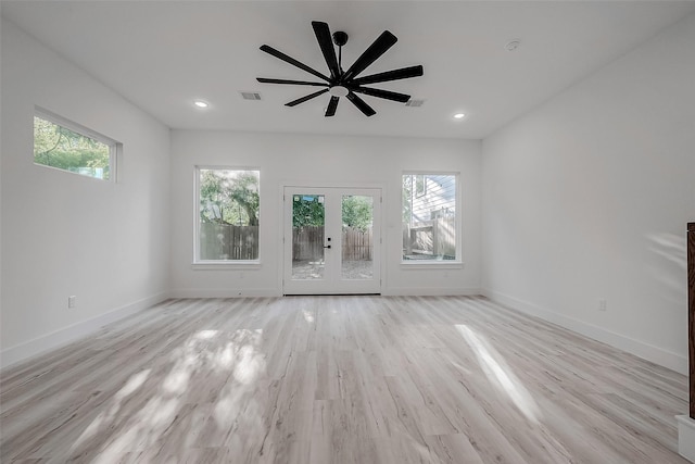 unfurnished living room with ceiling fan, light hardwood / wood-style flooring, a wealth of natural light, and french doors