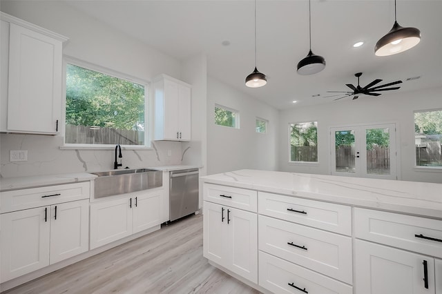 kitchen with hanging light fixtures, white cabinetry, sink, and stainless steel dishwasher