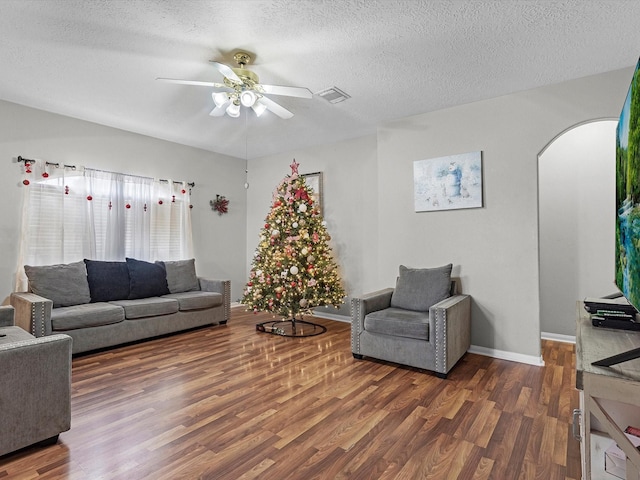 living room featuring dark hardwood / wood-style floors, ceiling fan, and a textured ceiling