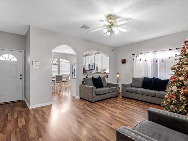 living room featuring a textured ceiling, hardwood / wood-style flooring, and ceiling fan