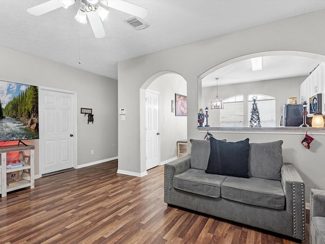 living room with a textured ceiling, dark hardwood / wood-style flooring, and ceiling fan with notable chandelier