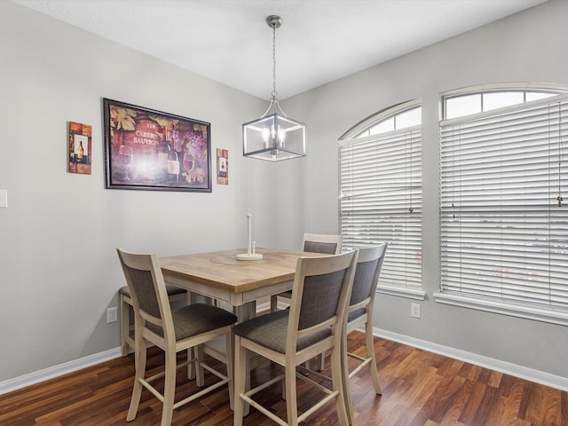 dining space featuring dark wood-type flooring and a notable chandelier