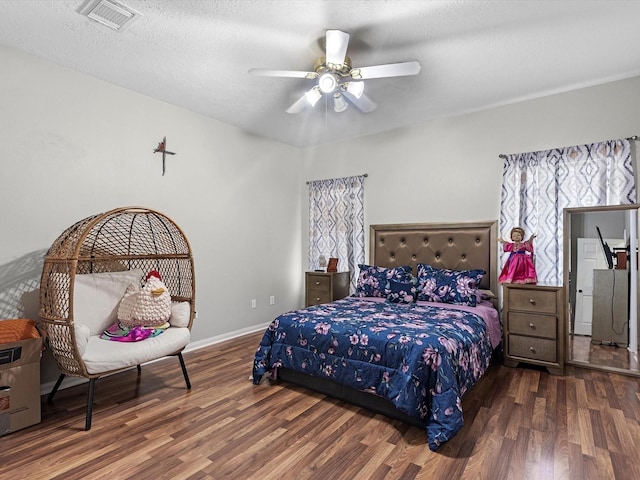 bedroom with a textured ceiling, ceiling fan, and dark hardwood / wood-style floors