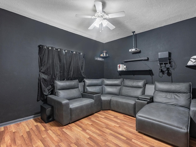 cinema room featuring ceiling fan, a textured ceiling, and light wood-type flooring