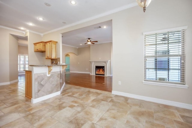 kitchen featuring a kitchen bar, kitchen peninsula, ornamental molding, and light brown cabinetry