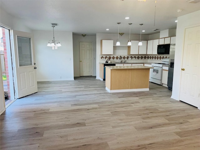 kitchen featuring white gas stove, white cabinetry, plenty of natural light, and hanging light fixtures