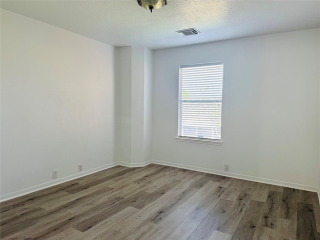 empty room featuring a textured ceiling and hardwood / wood-style flooring