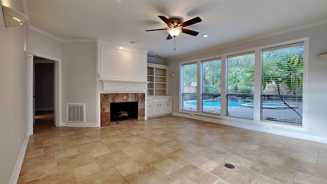 unfurnished living room featuring ceiling fan, crown molding, a fireplace, and built in shelves