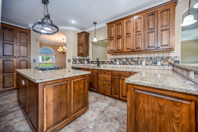 kitchen featuring a kitchen island, pendant lighting, backsplash, gas cooktop, and light stone countertops