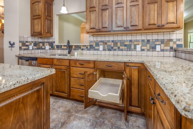 kitchen featuring hanging light fixtures, sink, stainless steel dishwasher, and light stone counters