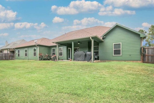 back of property featuring ceiling fan and a yard