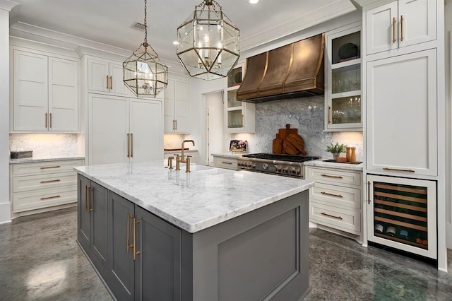 kitchen with premium range hood, beverage cooler, white cabinets, gray cabinets, and an island with sink