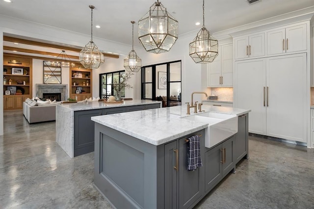 kitchen with a center island with sink, decorative light fixtures, white cabinets, and sink