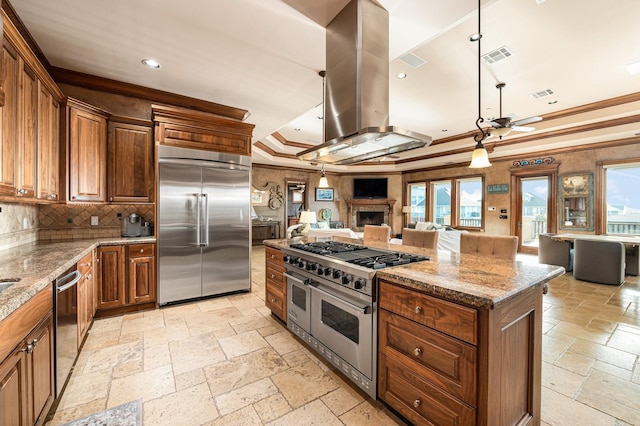 1245 Lagoon Dr, Crystal Beach, TX 77650 - kitchen featuring high end appliances, light stone countertops, a tray ceiling, a kitchen island, and island exhaust hood