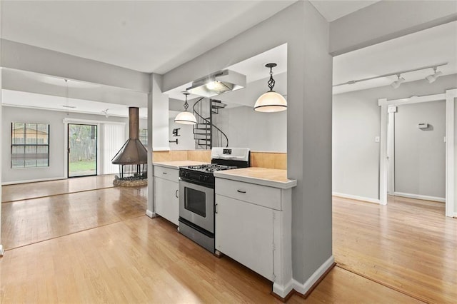 kitchen with pendant lighting, white cabinetry, light hardwood / wood-style flooring, and stainless steel gas range