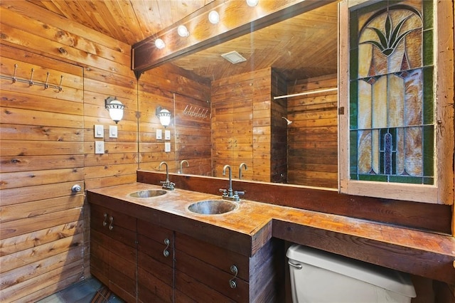 bathroom featuring vanity, toilet, wooden walls, and wood ceiling