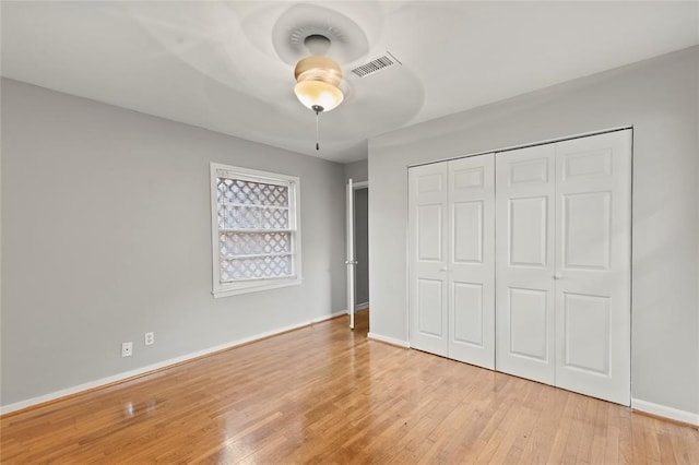 unfurnished bedroom with ceiling fan, light wood-type flooring, and a closet