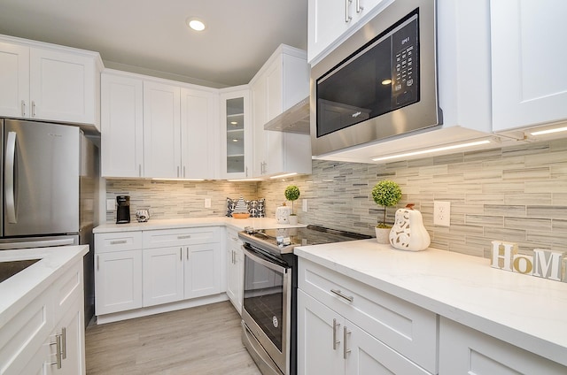 kitchen featuring white cabinets, decorative backsplash, stainless steel appliances, and light hardwood / wood-style floors