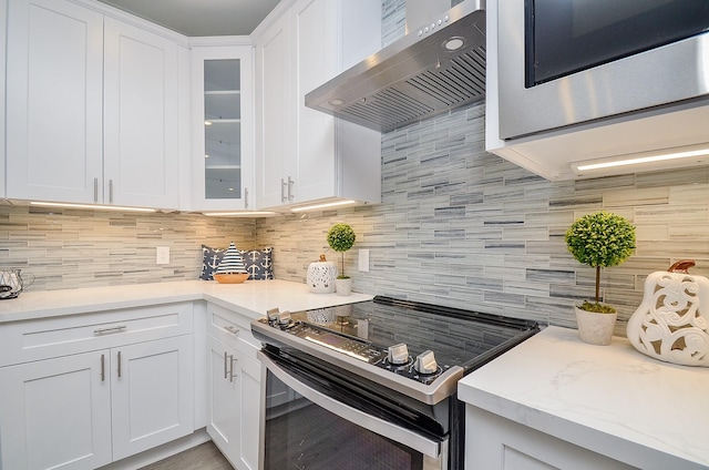 kitchen with white cabinets, appliances with stainless steel finishes, backsplash, and wall chimney exhaust hood