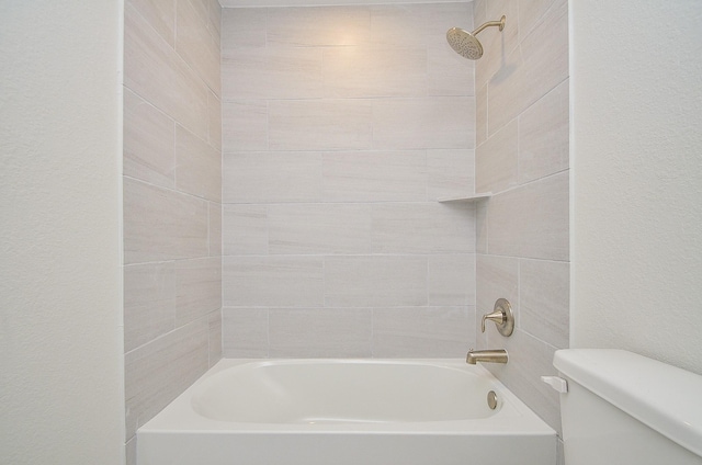 bathroom featuring toilet and tiled shower / bath