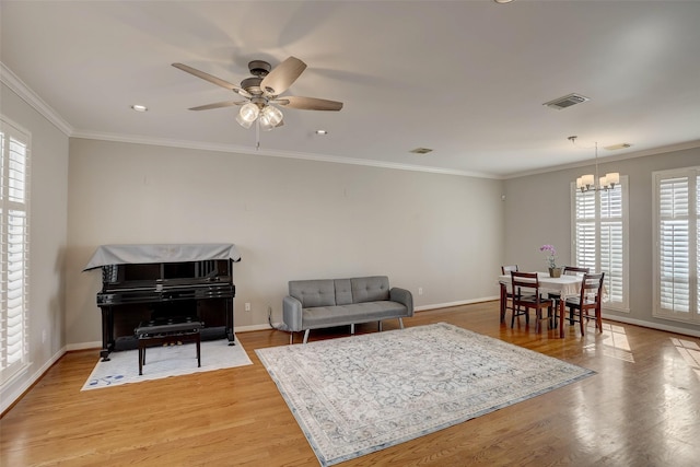 living room with ornamental molding, ceiling fan with notable chandelier, and hardwood / wood-style flooring