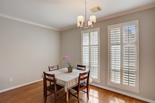 dining space with wood-type flooring, crown molding, a wealth of natural light, and a chandelier