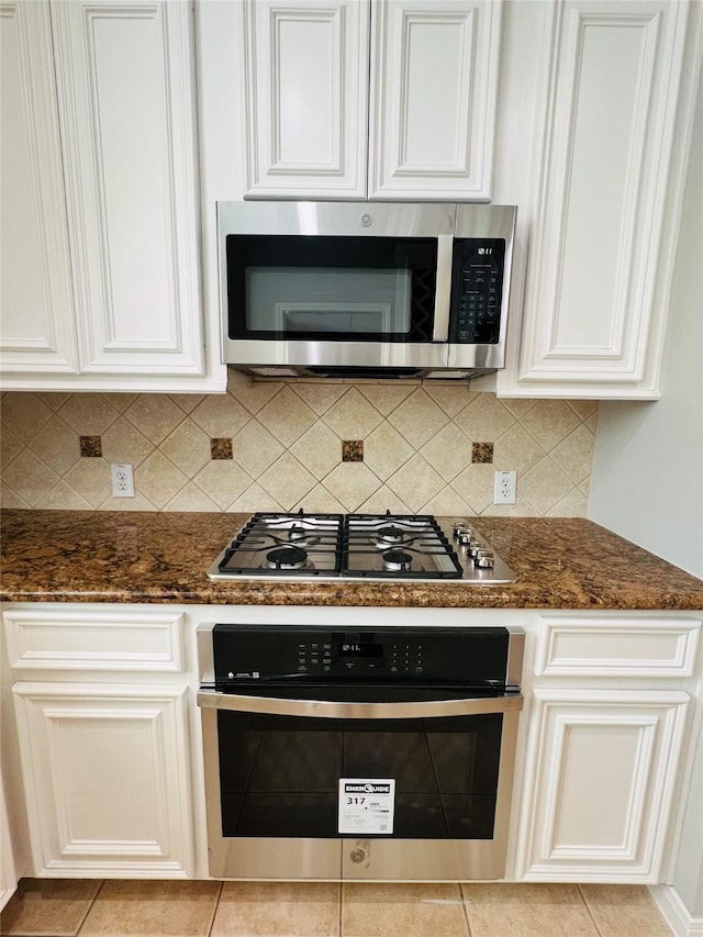 kitchen featuring dark stone countertops, white cabinetry, and appliances with stainless steel finishes