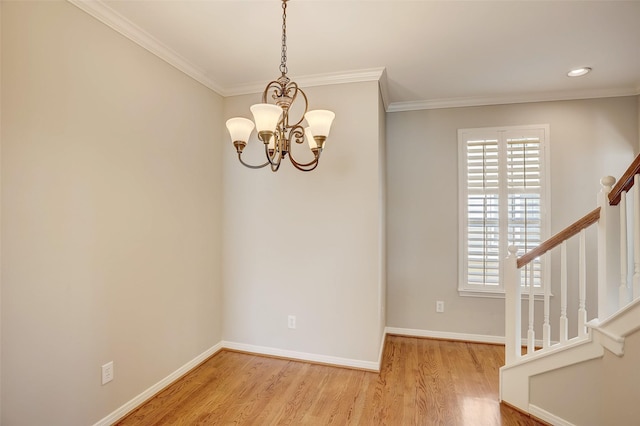 empty room with a notable chandelier, light wood-type flooring, and ornamental molding