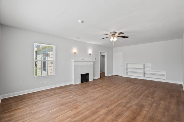 unfurnished living room featuring hardwood / wood-style floors, ceiling fan, and a premium fireplace