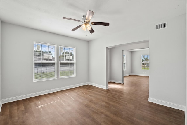 empty room with ceiling fan, dark hardwood / wood-style flooring, and a wealth of natural light