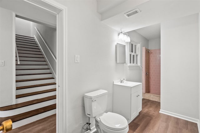 bathroom with tiled shower, wood-type flooring, vanity, and toilet