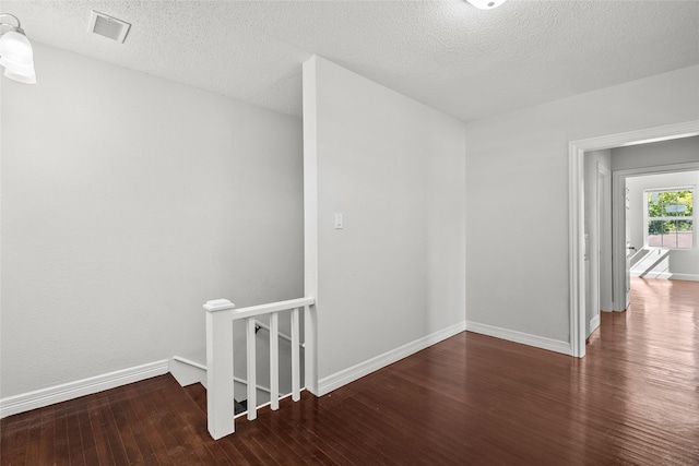 unfurnished room with dark hardwood / wood-style flooring and a textured ceiling