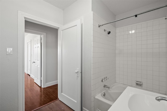 bathroom with sink, tiled shower / bath, a textured ceiling, and hardwood / wood-style flooring