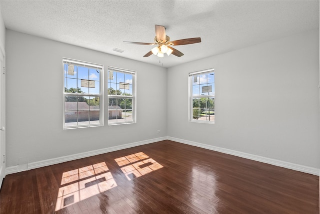 unfurnished room featuring dark hardwood / wood-style flooring, ceiling fan, plenty of natural light, and a textured ceiling