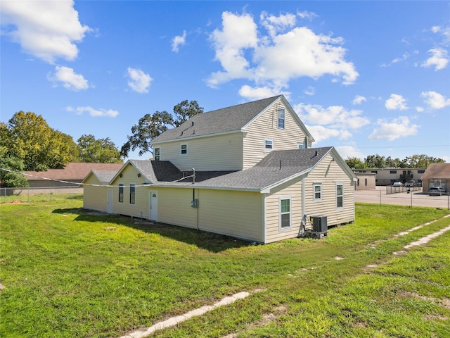 back of property featuring central AC unit and a yard