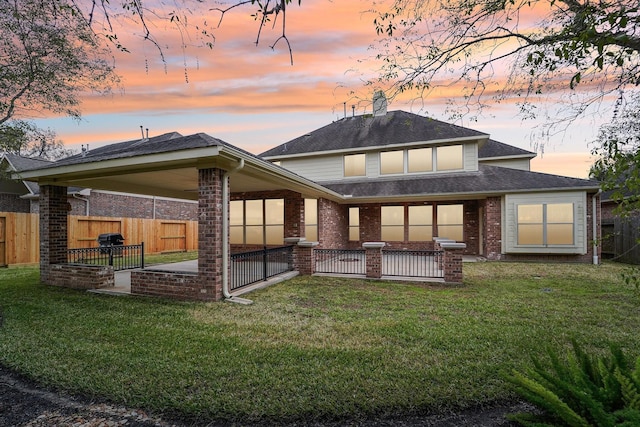 back house at dusk with a yard and a patio area