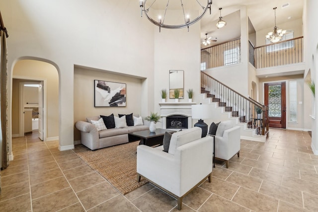 tiled living room with a towering ceiling and ceiling fan with notable chandelier