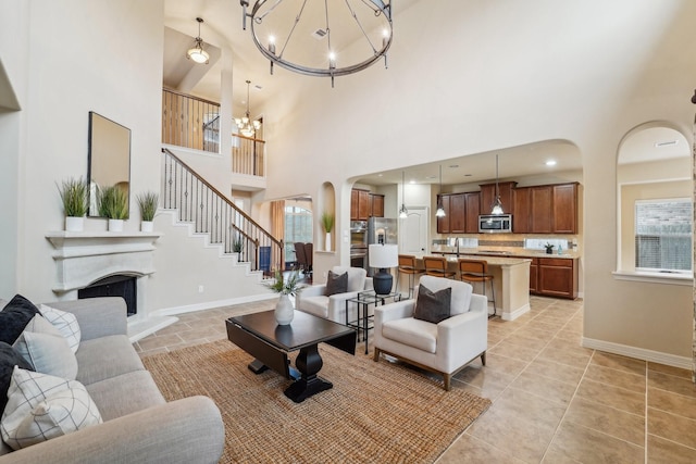 living room featuring plenty of natural light, high vaulted ceiling, and a notable chandelier