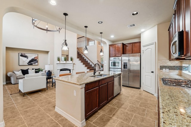 kitchen featuring pendant lighting, sink, appliances with stainless steel finishes, tasteful backsplash, and light stone counters