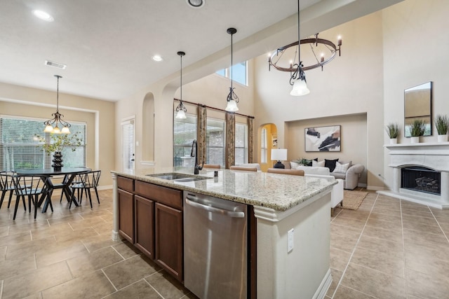 kitchen featuring light stone countertops, stainless steel dishwasher, sink, pendant lighting, and a chandelier