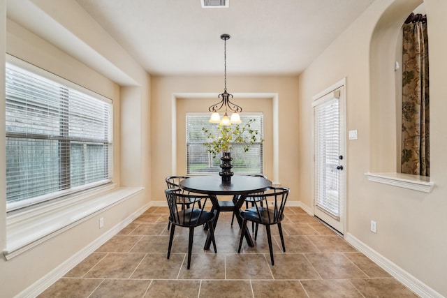 dining area featuring a healthy amount of sunlight, light tile patterned floors, and an inviting chandelier