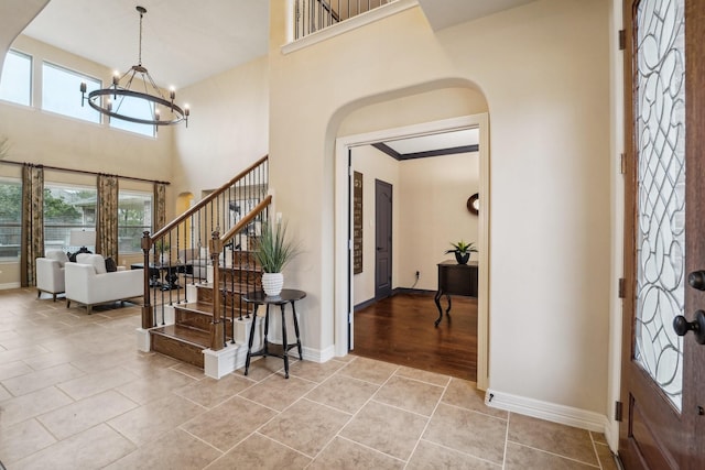 entrance foyer featuring light tile patterned floors, a towering ceiling, and an inviting chandelier