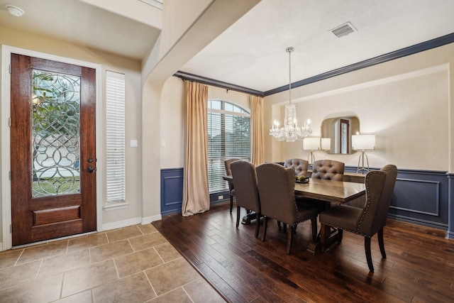 dining room with hardwood / wood-style flooring, a notable chandelier, and crown molding