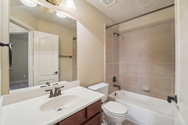 full bathroom with a textured ceiling, vanity, toilet, and tiled shower / bath