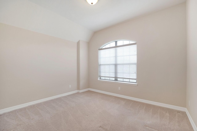 carpeted spare room with vaulted ceiling