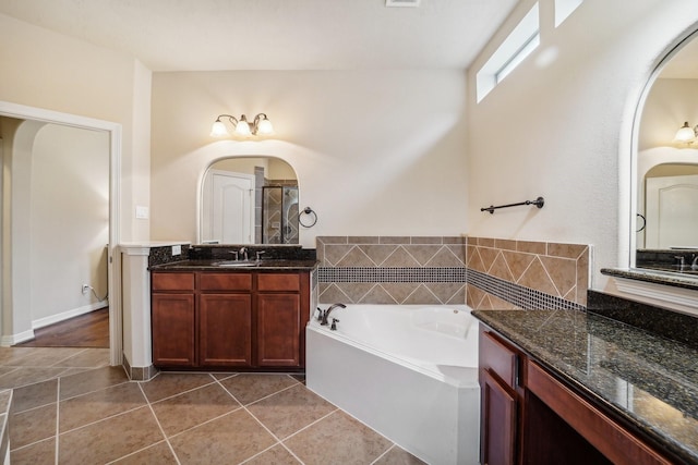 bathroom with a tub to relax in, tile patterned flooring, and vanity