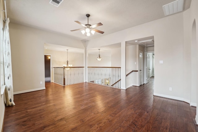 spare room with ceiling fan with notable chandelier and dark hardwood / wood-style floors